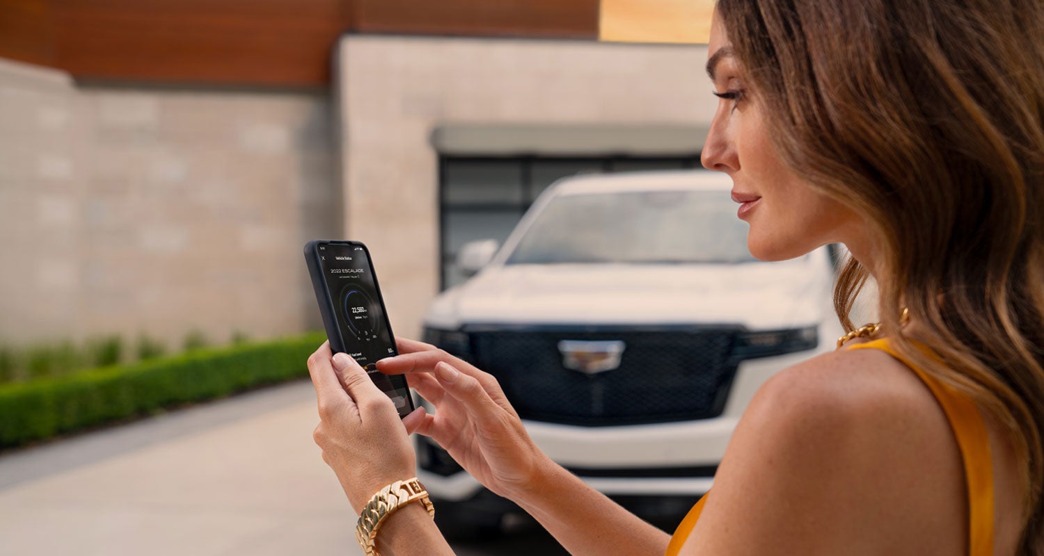 lady checking her mobile with a Cadillac vehicle background | Sheehan Cadillac in Pompano Beach FL