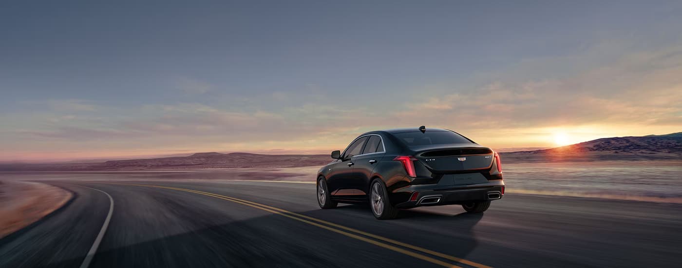 Rear of a black 2026 Cadillac CT4 driving on an open road