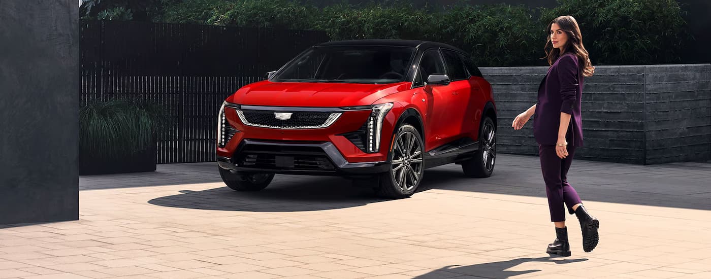 Woman walking towards a parked red 2026 Cadillac OPTIQ
