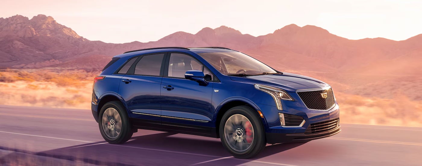 Blue 2026 Cadillac XT6 driving down a road.