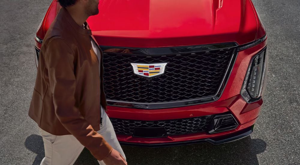 Front grille of a red 2027 Cadillac Escalade V ESV with a man walking in front.