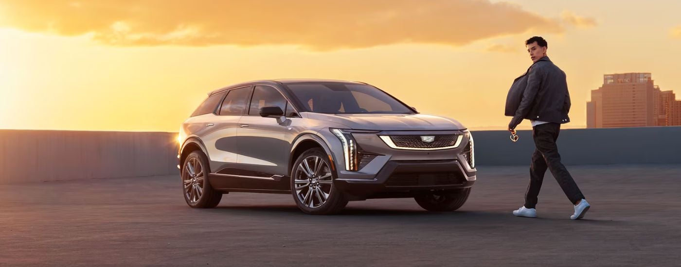 A silver 2027 Cadillac OPTIQ parked on a rooftop by a man.