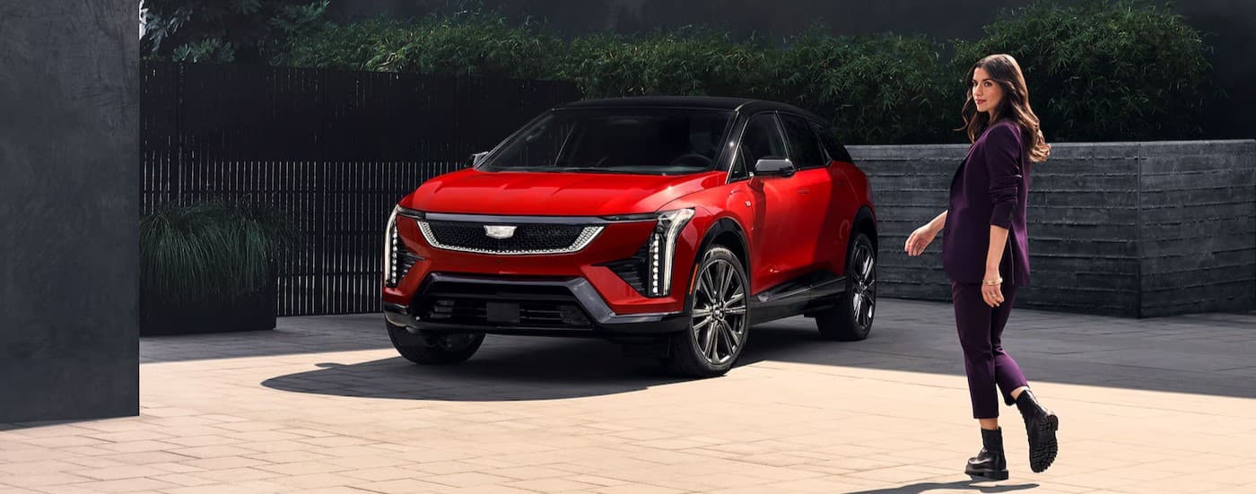A red 2026 Cadillac OPTIQ parked near a person walking.