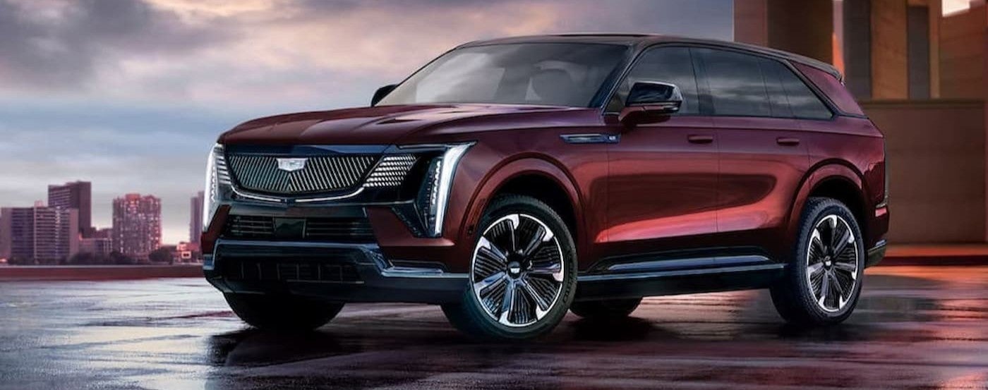 A maroon 2026 Cadillac Escalade IQ parked near a city.