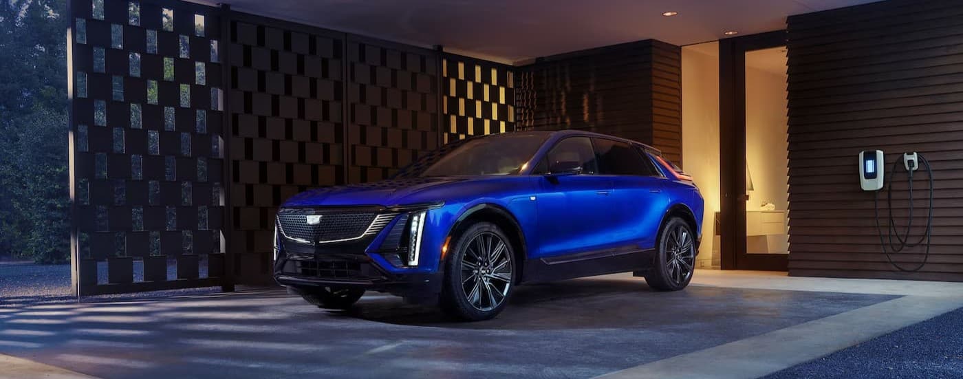 A blue 2026 Cadillac LYRIQ parked near a house.