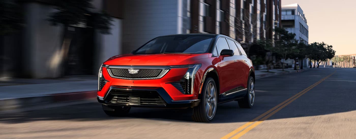 A red 2026 Cadillac OPTIQ-V driving in a city.