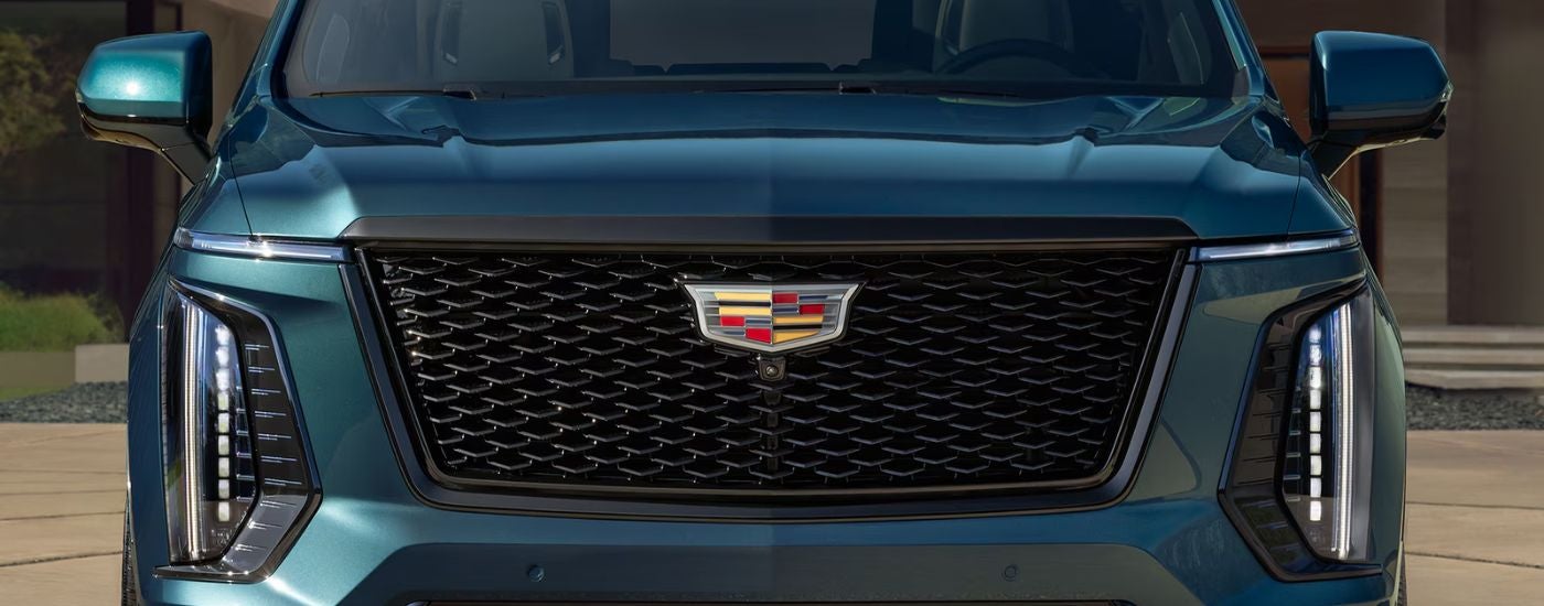 Front grille of a blue 2026 Cadillac Escalade parked in a driveway.