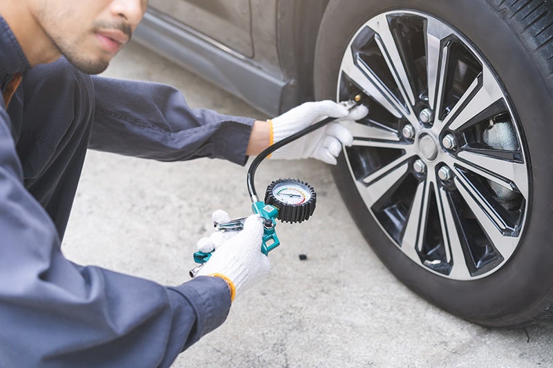 A technition inspecting a tire pressure